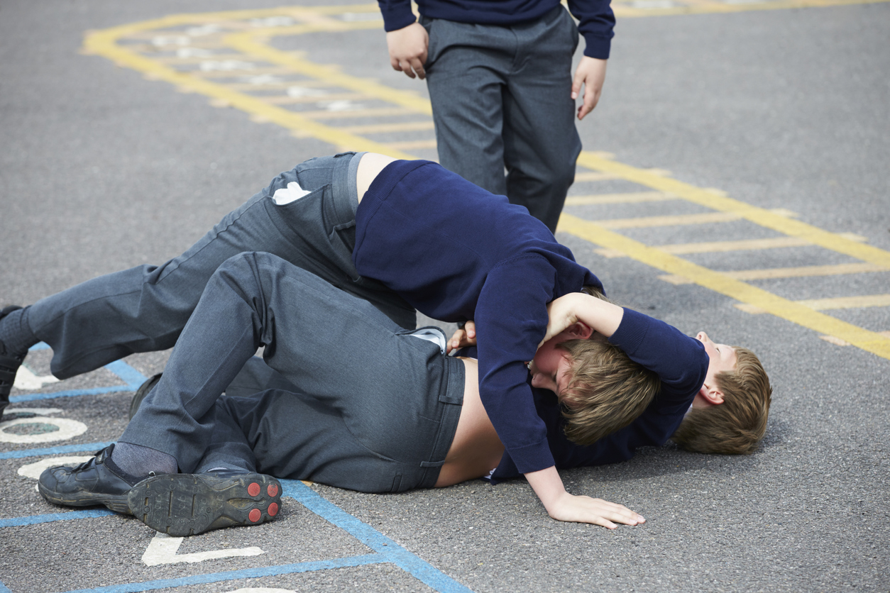 Two Boys Fighting In School Playground During Break Time