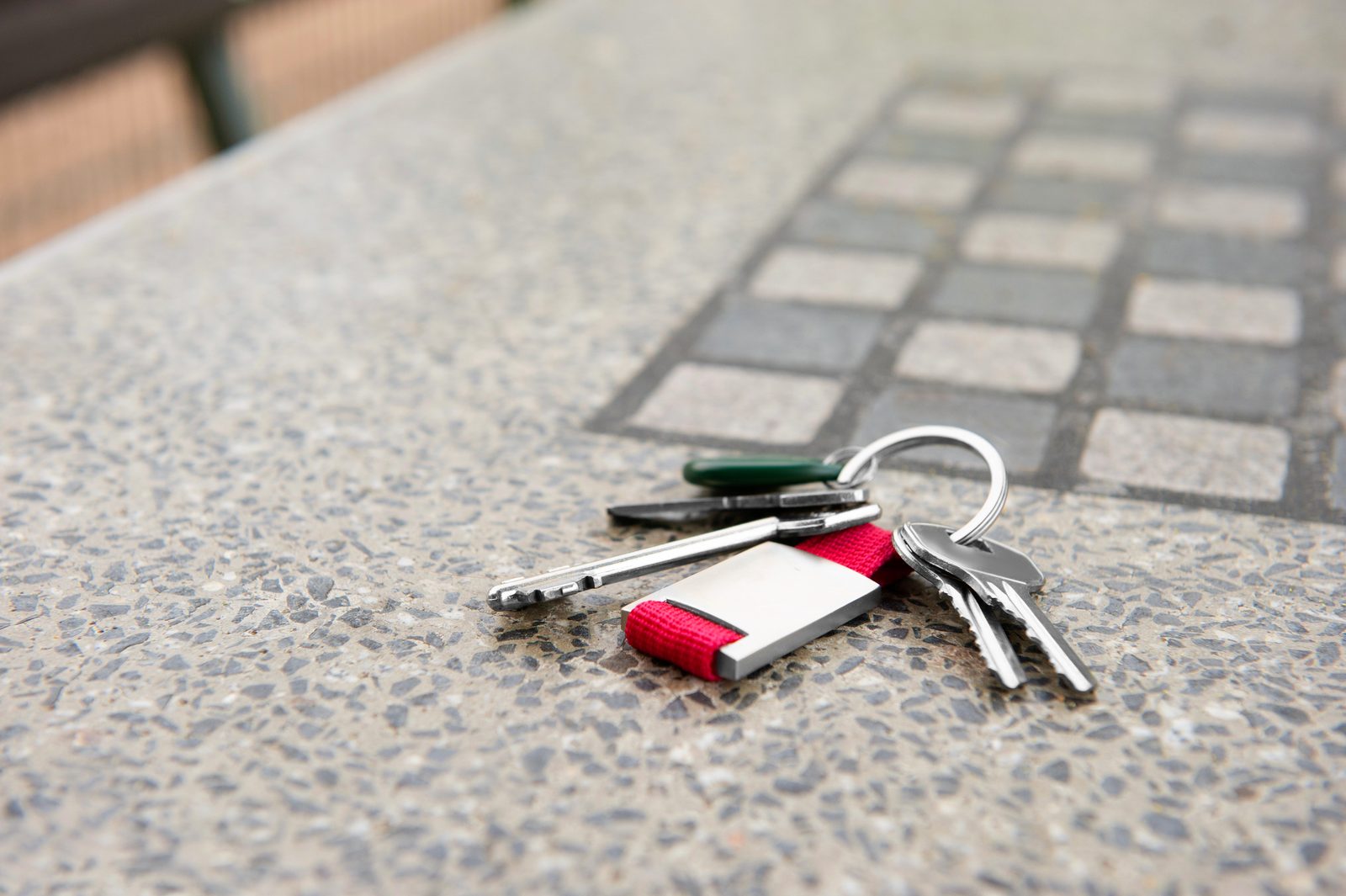 Set of keys with a red tag resting on a stone surface